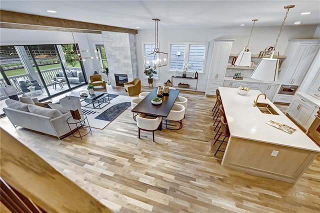 living room featuring light wood-type flooring, sink, a healthy amount of sunlight, and a tiled fireplace