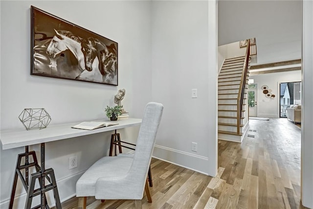 office featuring beamed ceiling, built in desk, and light hardwood / wood-style flooring