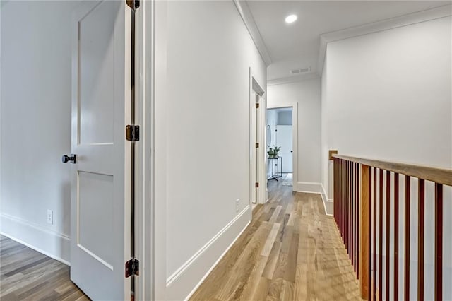 hallway featuring crown molding and light hardwood / wood-style flooring