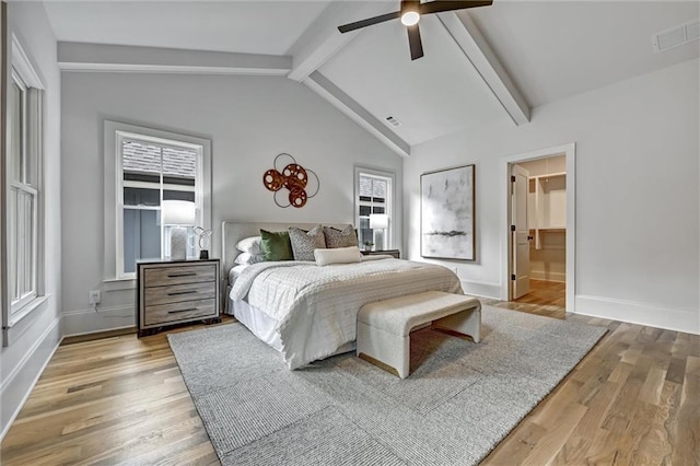 bedroom with hardwood / wood-style flooring, ceiling fan, lofted ceiling with beams, and multiple windows