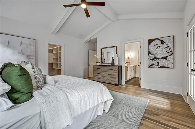 bedroom featuring connected bathroom, ceiling fan, lofted ceiling with beams, a walk in closet, and a closet