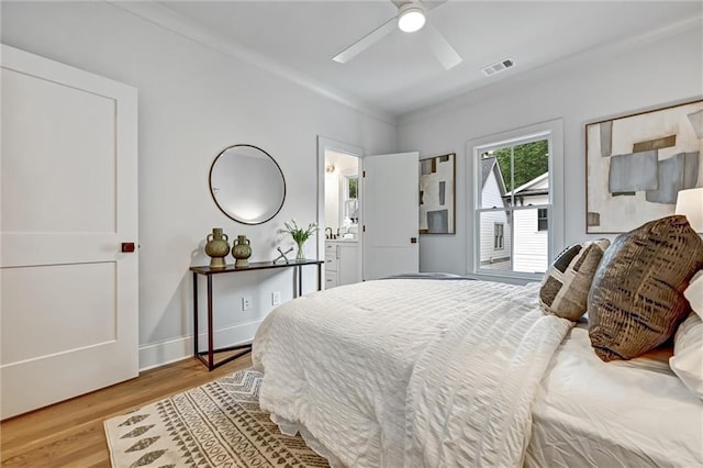 bedroom featuring light hardwood / wood-style floors, ceiling fan, ornamental molding, and ensuite bathroom