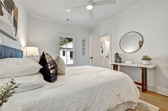 bedroom with connected bathroom, light hardwood / wood-style flooring, ceiling fan, and crown molding