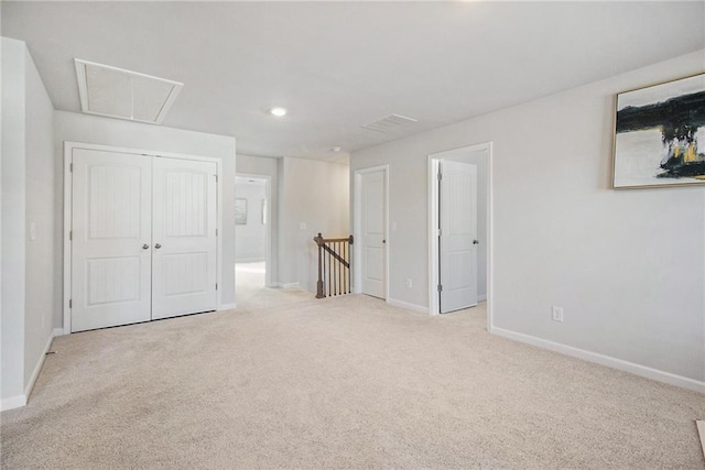 unfurnished bedroom with a closet and light colored carpet