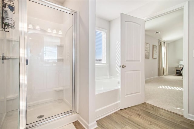 bathroom with wood-type flooring and shower with separate bathtub