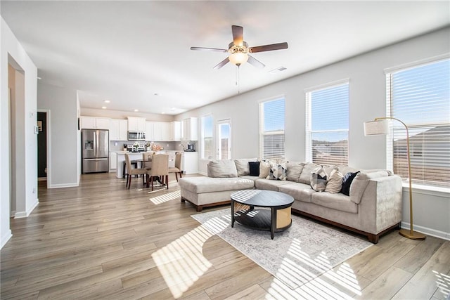 living room featuring a wealth of natural light, ceiling fan, and light wood-type flooring