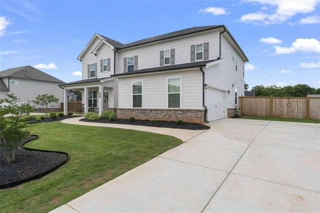 traditional home featuring a garage, driveway, fence, a front lawn, and brick siding