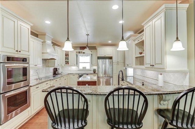 kitchen with light stone counters, backsplash, pendant lighting, and stainless steel appliances
