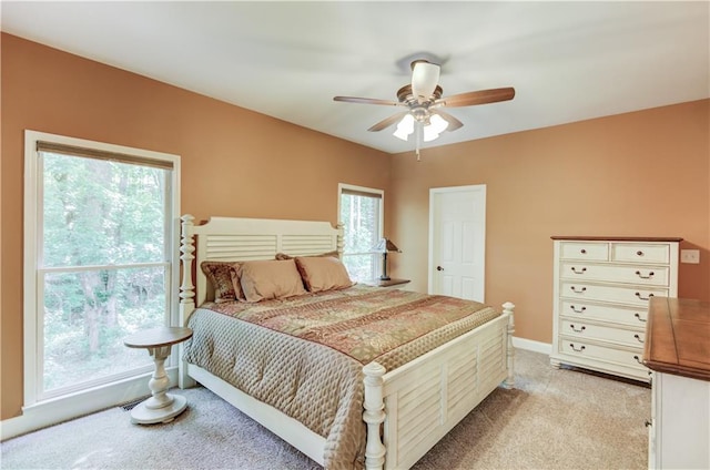 bedroom featuring multiple windows, light colored carpet, and ceiling fan