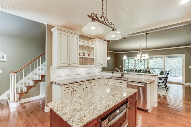 kitchen with pendant lighting, sink, stainless steel appliances, a center island, and light stone countertops