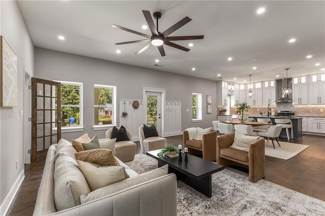 living room with sink, ceiling fan, and dark wood-type flooring