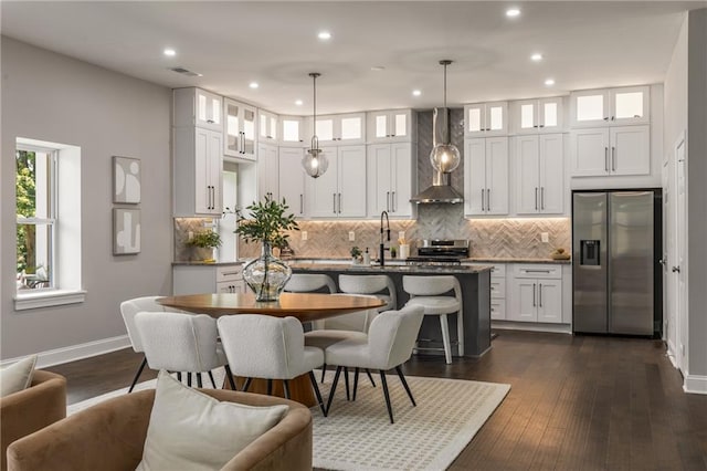 kitchen with a center island with sink, decorative light fixtures, white cabinets, and appliances with stainless steel finishes