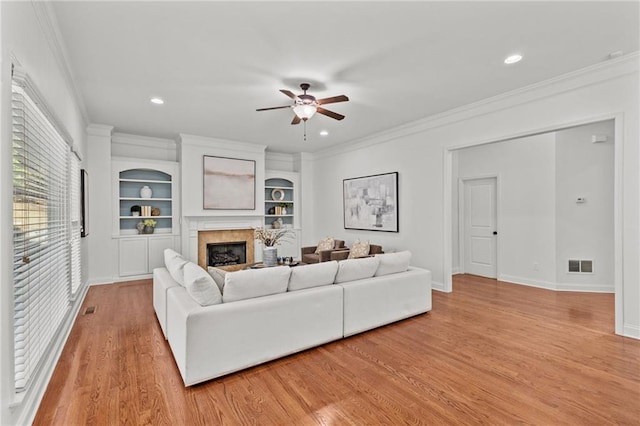 living room featuring crown molding, light hardwood / wood-style floors, and built in features