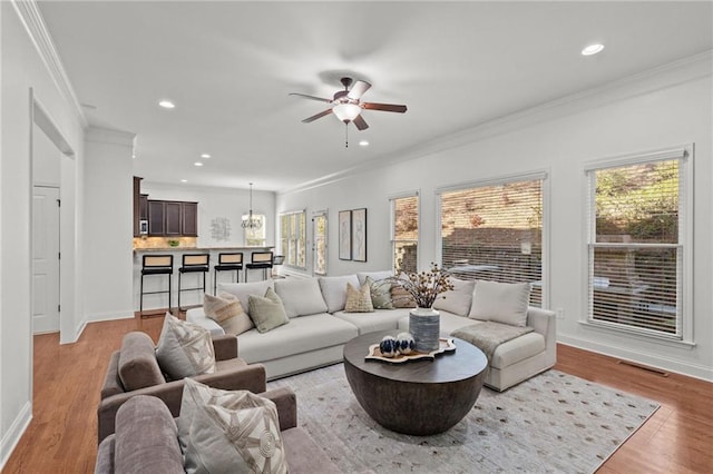 living room featuring crown molding, ceiling fan, and light hardwood / wood-style floors