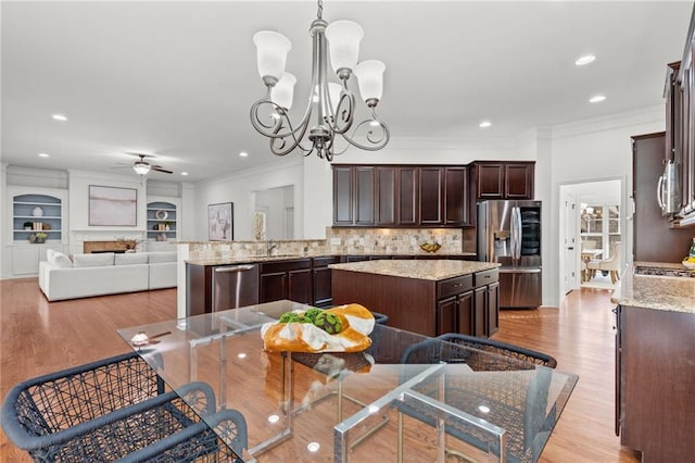 kitchen featuring hanging light fixtures, ornamental molding, a kitchen island, and stainless steel appliances