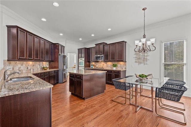 kitchen with a kitchen island, decorative light fixtures, sink, stainless steel appliances, and dark brown cabinets