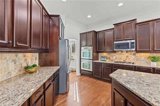 kitchen featuring light stone counters, stainless steel appliances, light hardwood / wood-style floors, and decorative backsplash