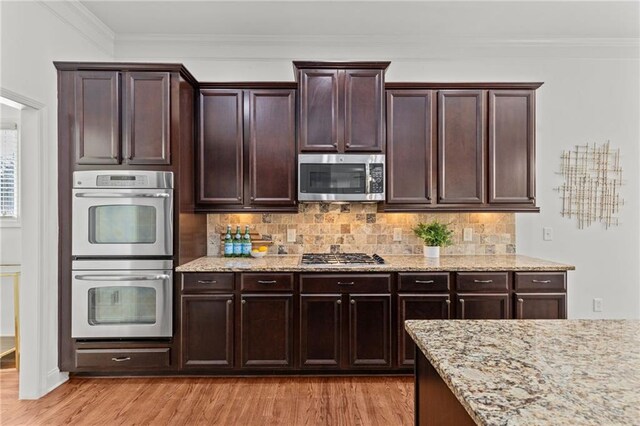 kitchen with tasteful backsplash, dark brown cabinetry, stainless steel appliances, and light hardwood / wood-style flooring