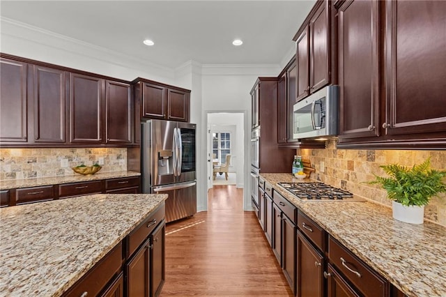 kitchen with light stone counters, ornamental molding, tasteful backsplash, and stainless steel appliances