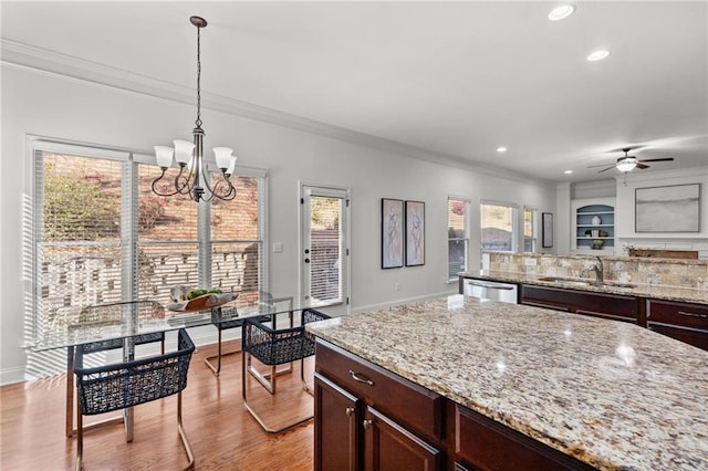 kitchen featuring crown molding, light stone countertops, stainless steel dishwasher, and pendant lighting