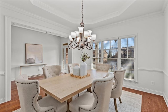 dining area featuring ornamental molding, hardwood / wood-style floors, a chandelier, and a tray ceiling