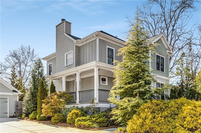 view of front of property featuring covered porch, board and batten siding, and a chimney