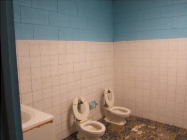 bathroom featuring tile walls, tile floors, toilet, and vanity