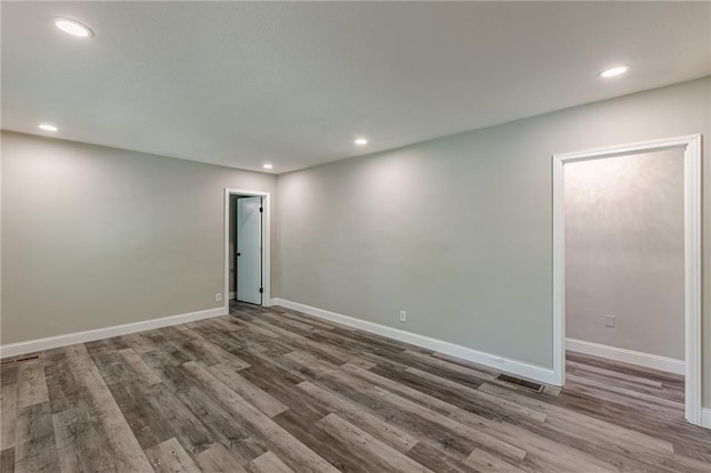 spare room featuring baseboards, wood finished floors, visible vents, and recessed lighting