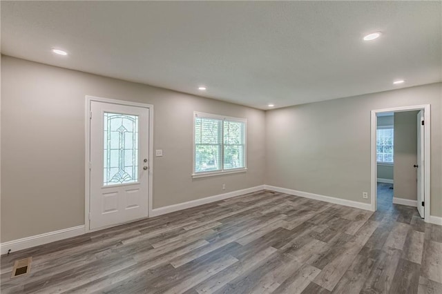 foyer featuring baseboards, wood finished floors, visible vents, and recessed lighting