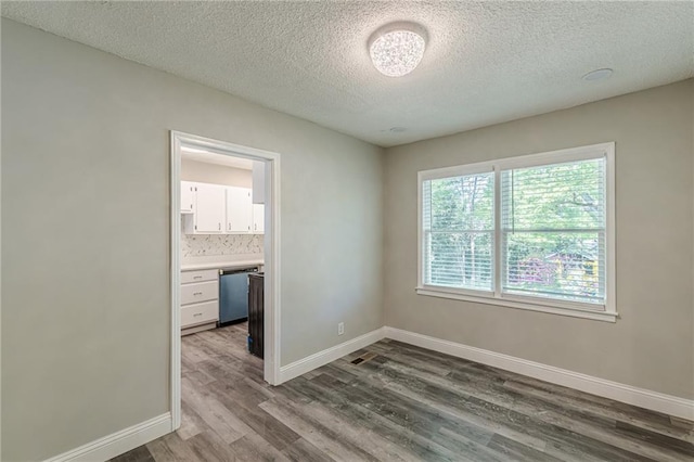 unfurnished room featuring a textured ceiling, baseboards, and dark wood-style flooring