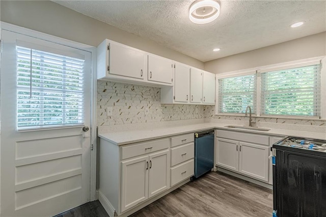 kitchen featuring white cabinets, a sink, a textured ceiling, dishwasher, and range