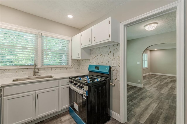 kitchen with tasteful backsplash, a textured ceiling, stainless steel electric range, and a sink