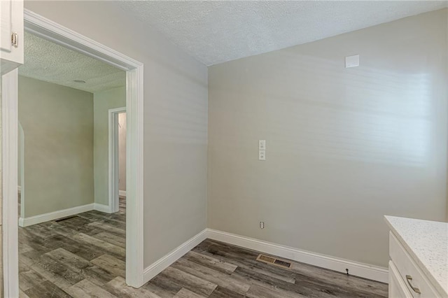 interior space with baseboards, dark wood-style flooring, a textured ceiling, and visible vents