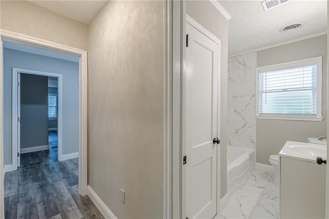 full bathroom with a washtub, vanity, baseboards, toilet, and visible vents