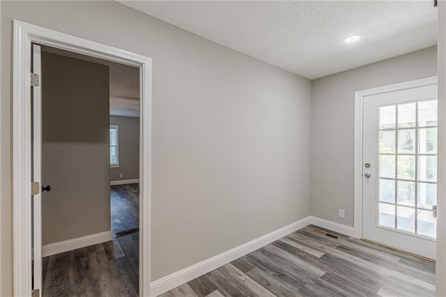 doorway with baseboards, wood finished floors, a textured ceiling, and recessed lighting