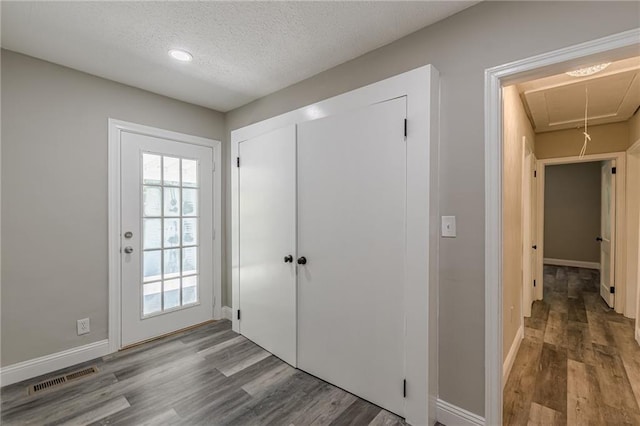 interior space with a wealth of natural light, wood finished floors, visible vents, and a textured ceiling