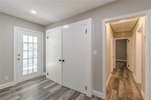 interior space featuring wood finished floors, a textured ceiling, a healthy amount of sunlight, baseboards, and visible vents