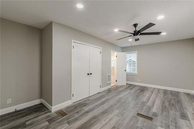 unfurnished bedroom featuring baseboards, wood finished floors, visible vents, and recessed lighting