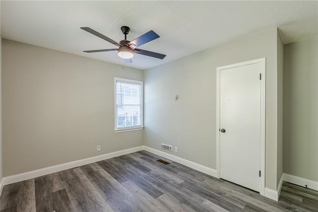 empty room with ceiling fan, baseboards, wood finished floors, and visible vents