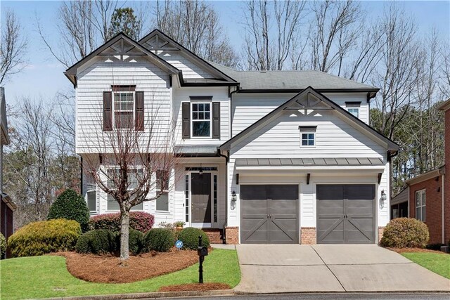 view of front of house featuring brick siding, driveway, and a standing seam roof