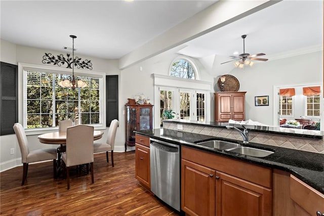 kitchen with dishwasher, sink, dark stone counters, hanging light fixtures, and dark wood-type flooring