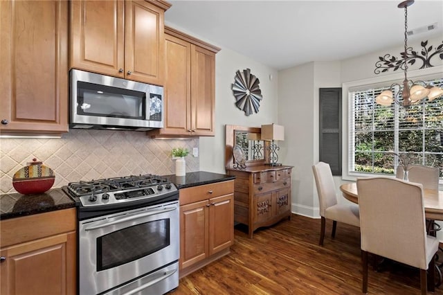 kitchen with dark stone countertops, backsplash, dark hardwood / wood-style flooring, hanging light fixtures, and stainless steel appliances