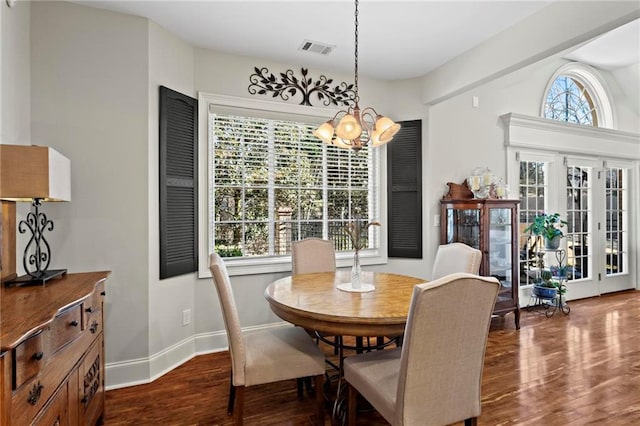 dining area with plenty of natural light, dark hardwood / wood-style floors, and a chandelier