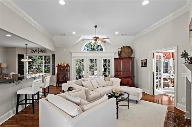 living room with ornamental molding, vaulted ceiling, dark wood-type flooring, and ceiling fan with notable chandelier