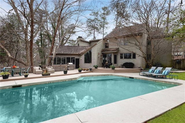 outdoor pool featuring a grill and a wooden deck