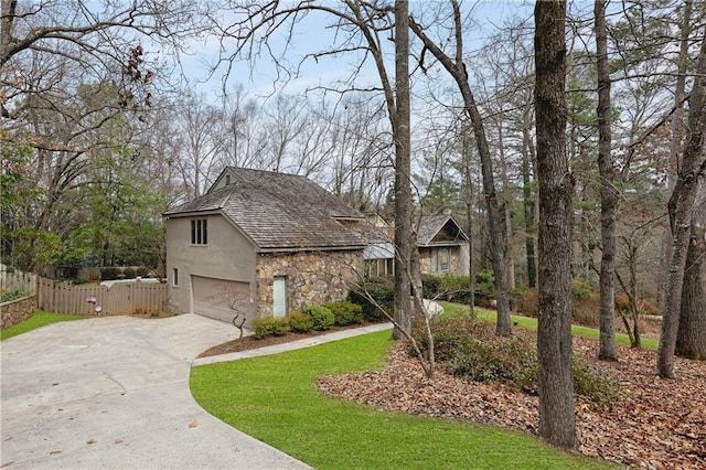 view of front of home featuring a garage, concrete driveway, stone siding, fence, and stucco siding