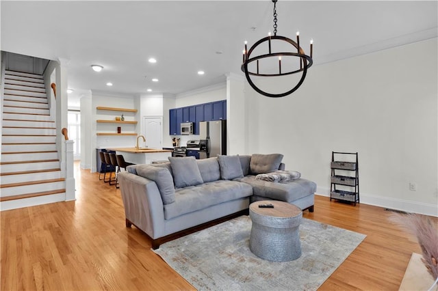 living room featuring light wood-style flooring, stairway, ornamental molding, a chandelier, and recessed lighting