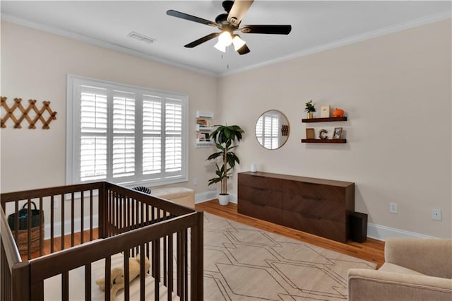 bedroom with light wood finished floors, visible vents, and crown molding