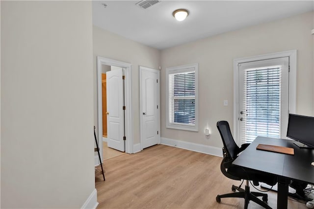 office space featuring light wood-style floors, baseboards, and visible vents