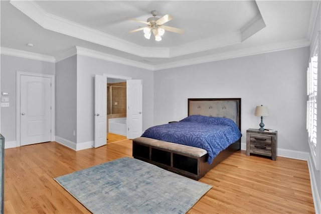 bedroom featuring a raised ceiling, light wood-style flooring, and baseboards